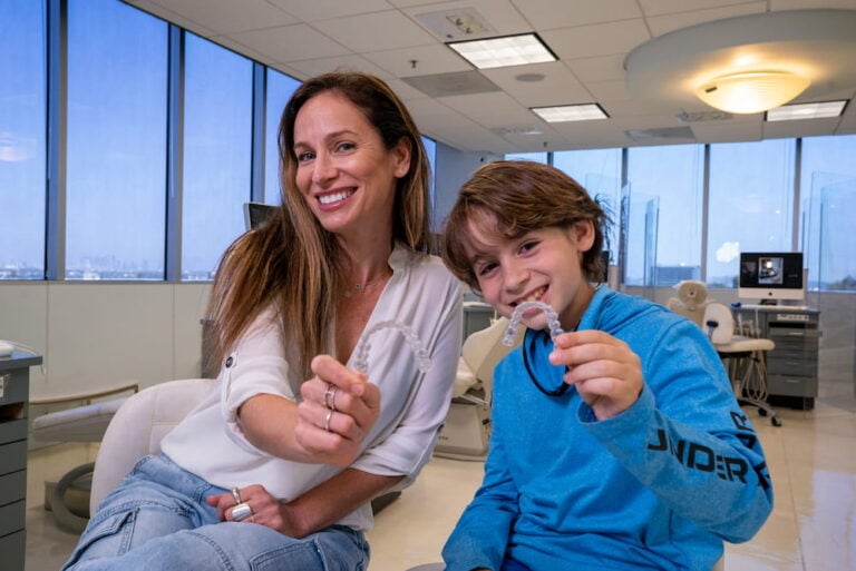 A young boy holds up his Invisalign retainer, showing off how inconspicuous it is.