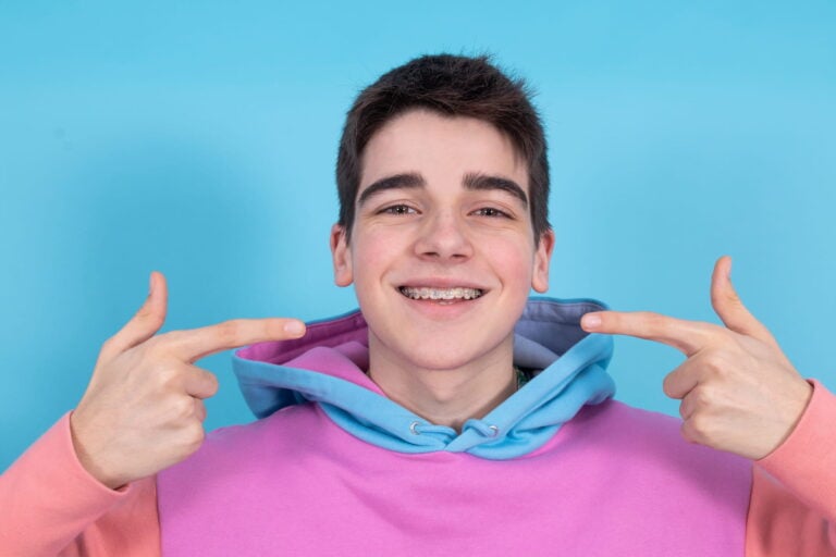 Young man pointing to braces while smiling