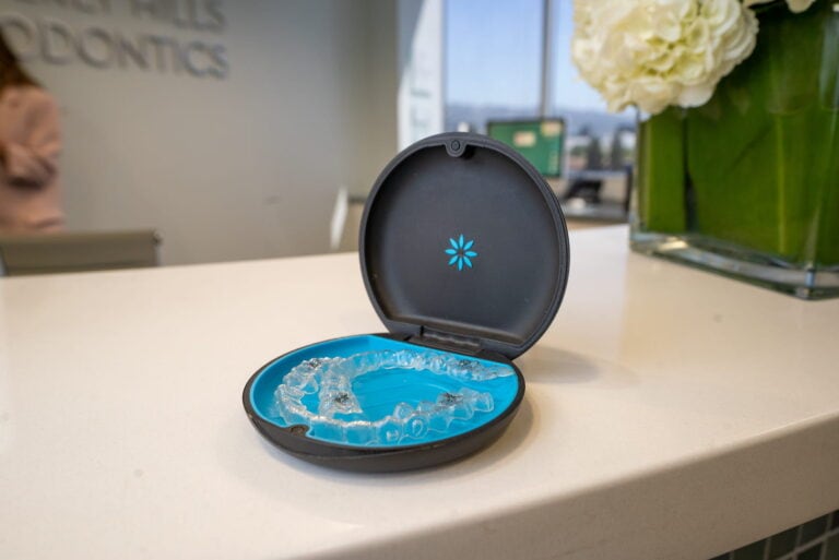 An image of a pair of Invisalign retainers sitting in their carrying case on a desk.
