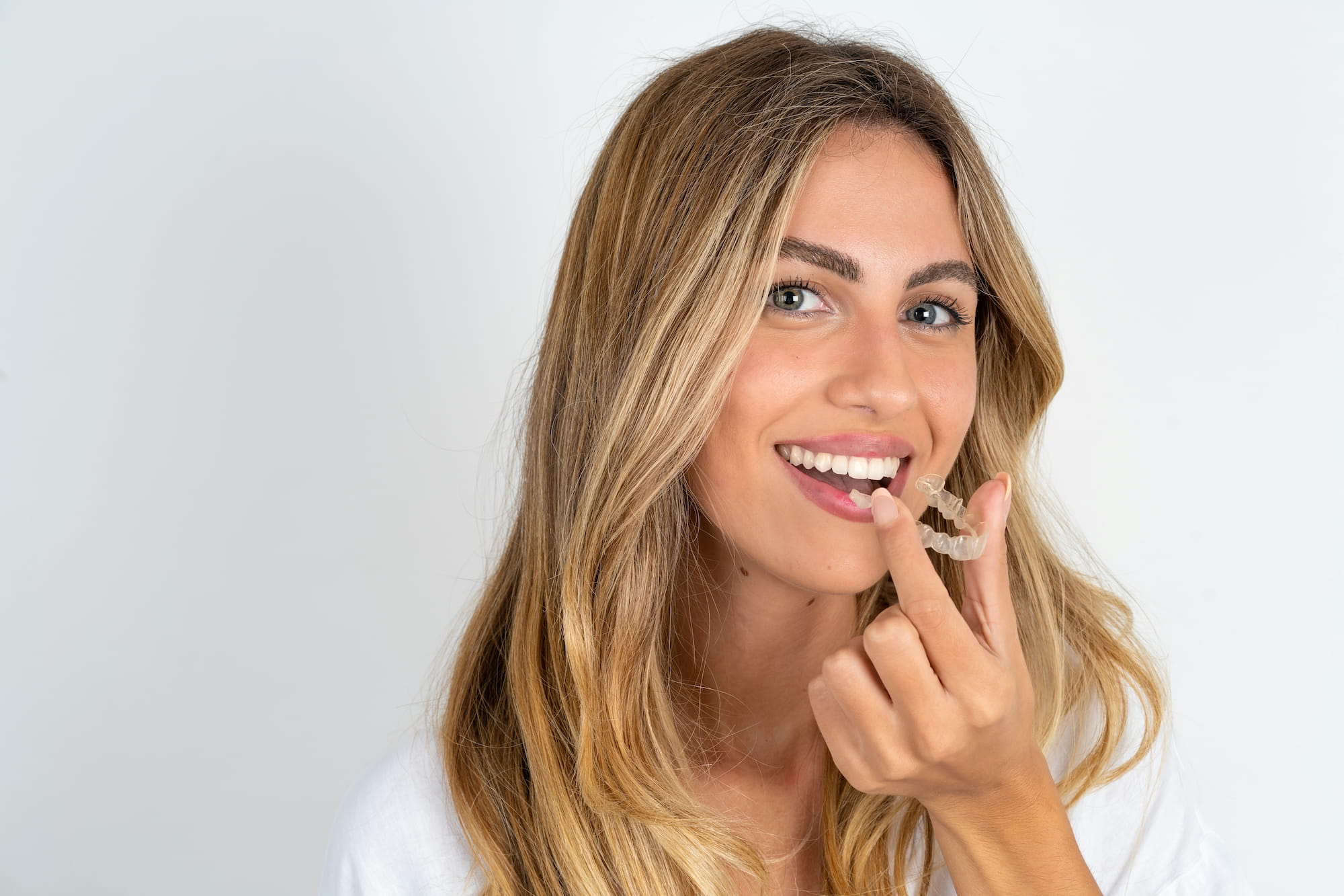 A woman shows off her gorgeous smile while effortlessly removing her Invisalign retainer.