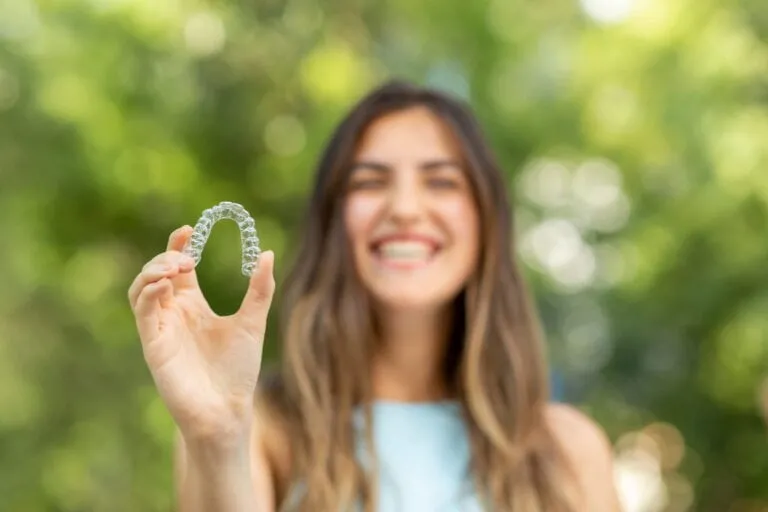 A lady holds up his Invisalign retainer, showing off how inconspicuous it is.