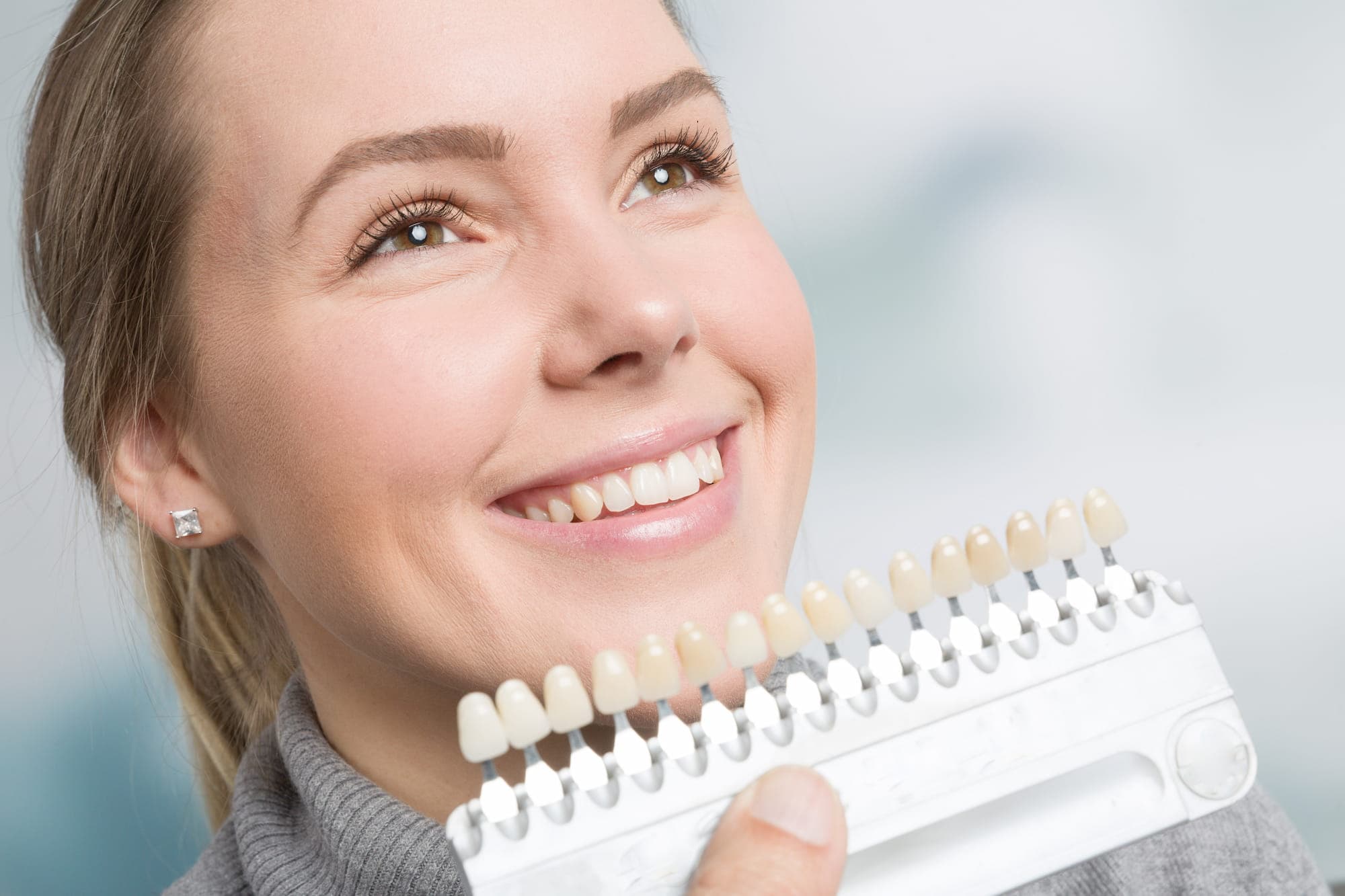 A woman admiring her teeth whitening before and after shade improvement