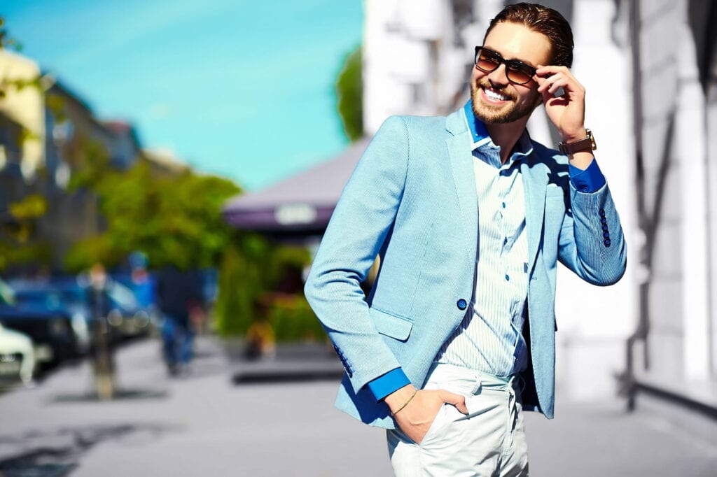A man with a gorgeous smile putting on sunglasses.